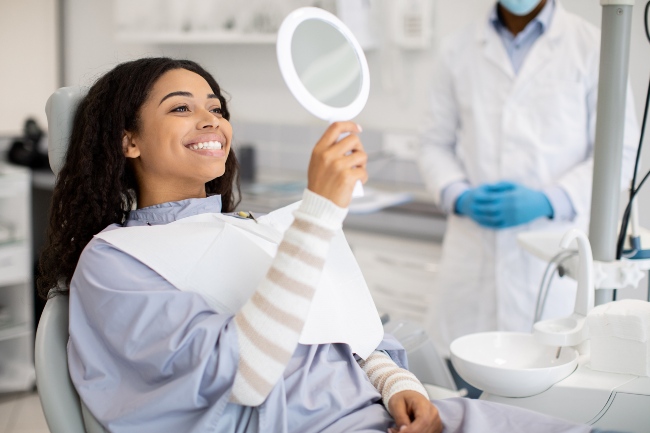 Happy patient admiring her bright smile after teeth whitening treatment in Fenton, MO