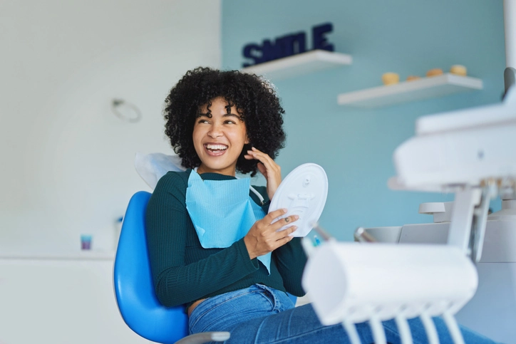 Person in a dental clinic holding a mirror, preparing for chipped tooth treatment in Fenton, MO